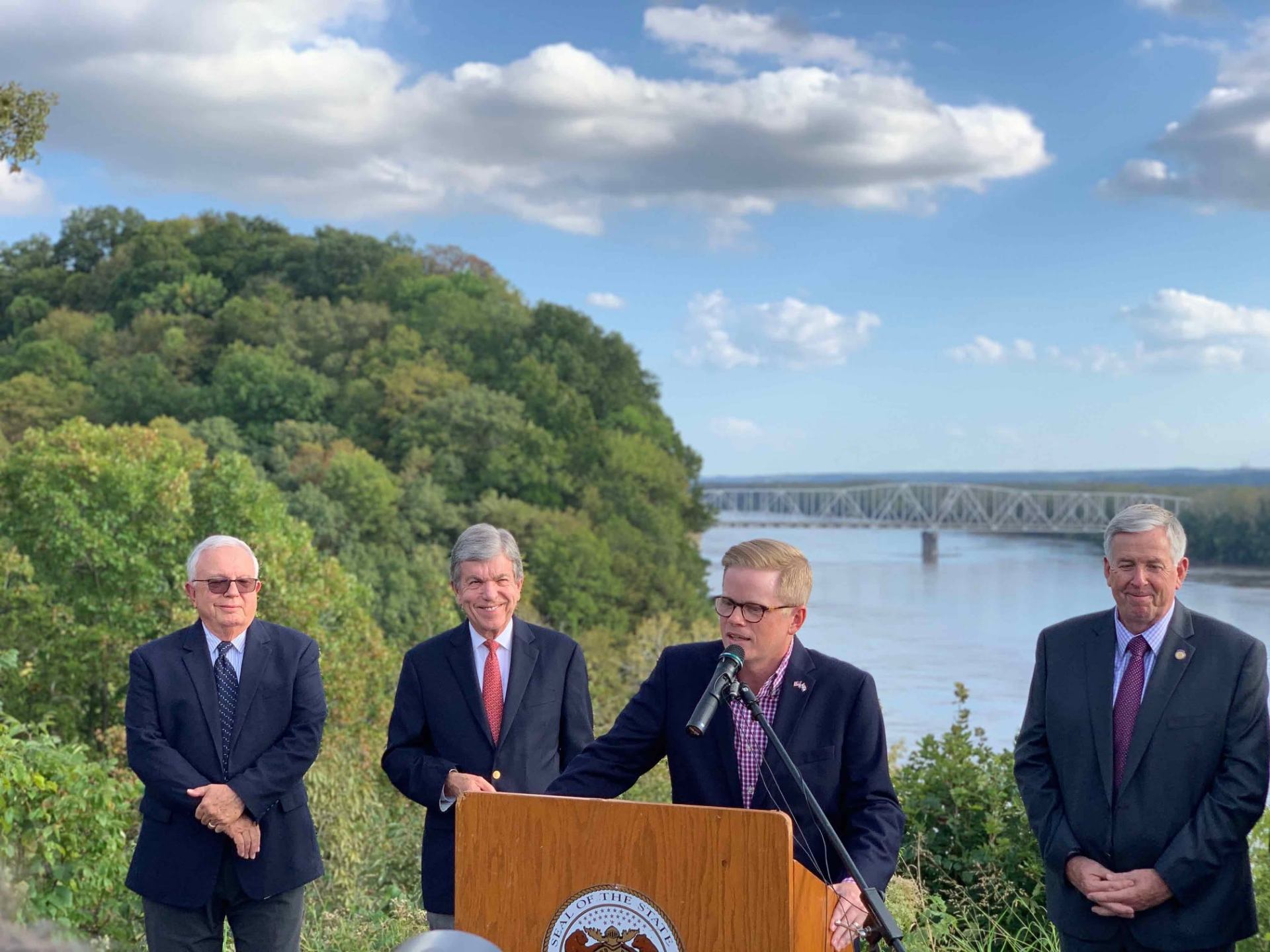 Caleb Rowden speaking at an outdoor press conference alongside state and federal officials